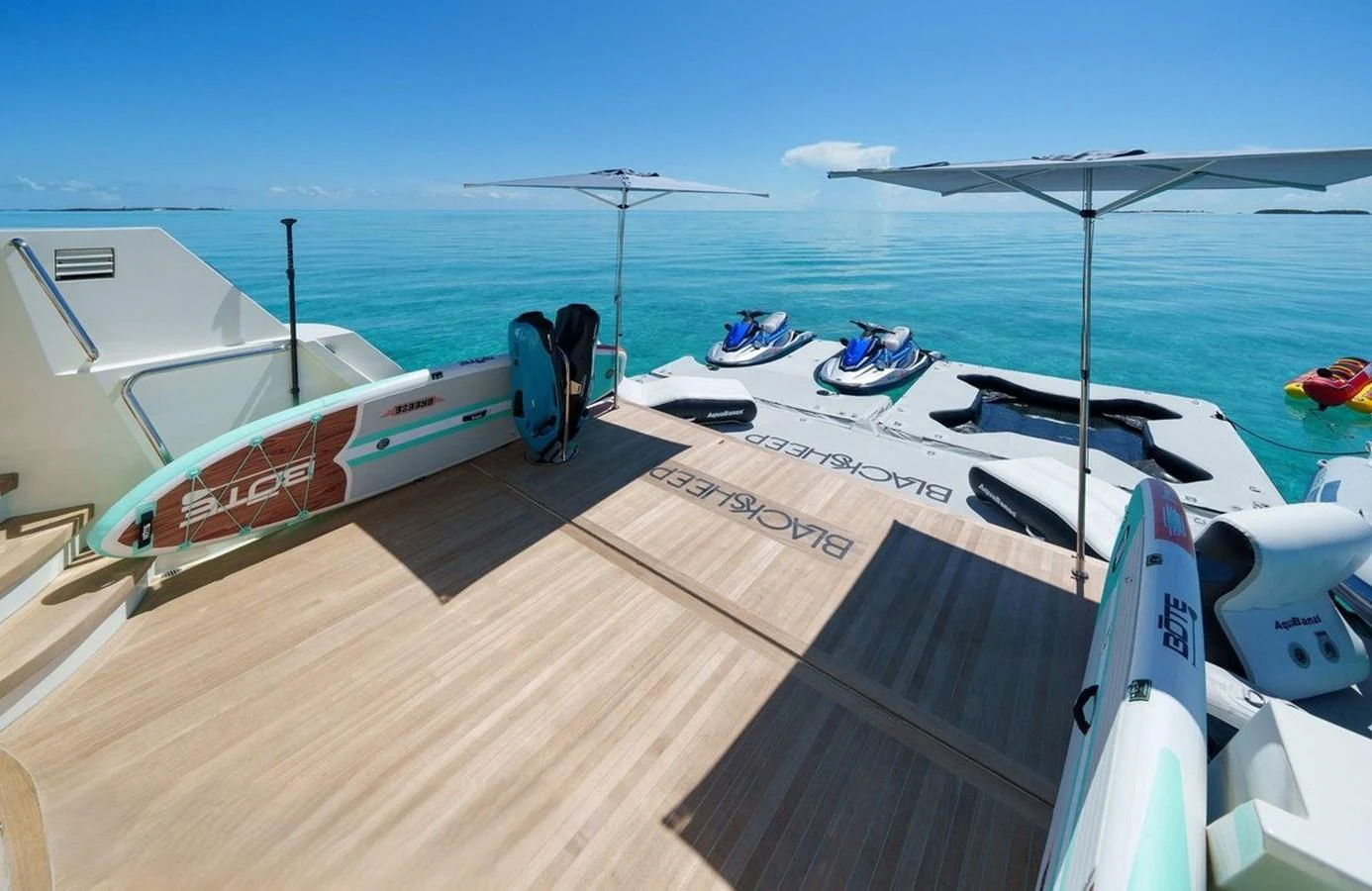 The yacht's beach club offers a serene space with water toys and sun umbrellas, perfect for relaxation and adventure. aboard BLACK SHEEP Yacht for Sale