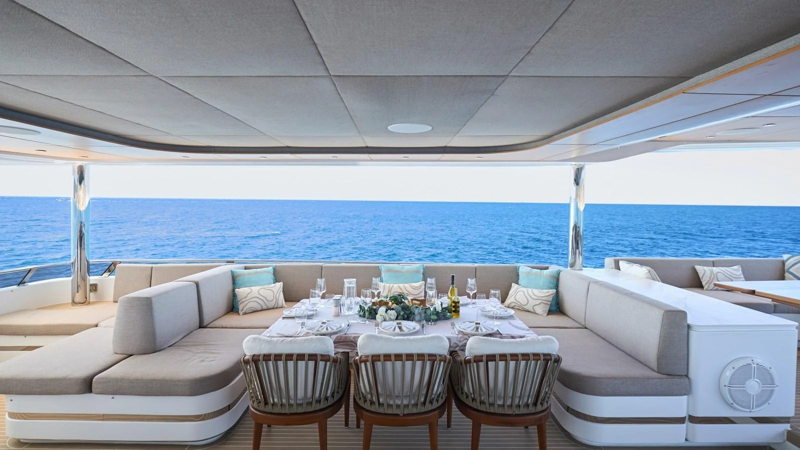 The aft deck features a luxurious dining area with a stunning ocean view. aboard ATRAVERSIA Yacht for Sale
