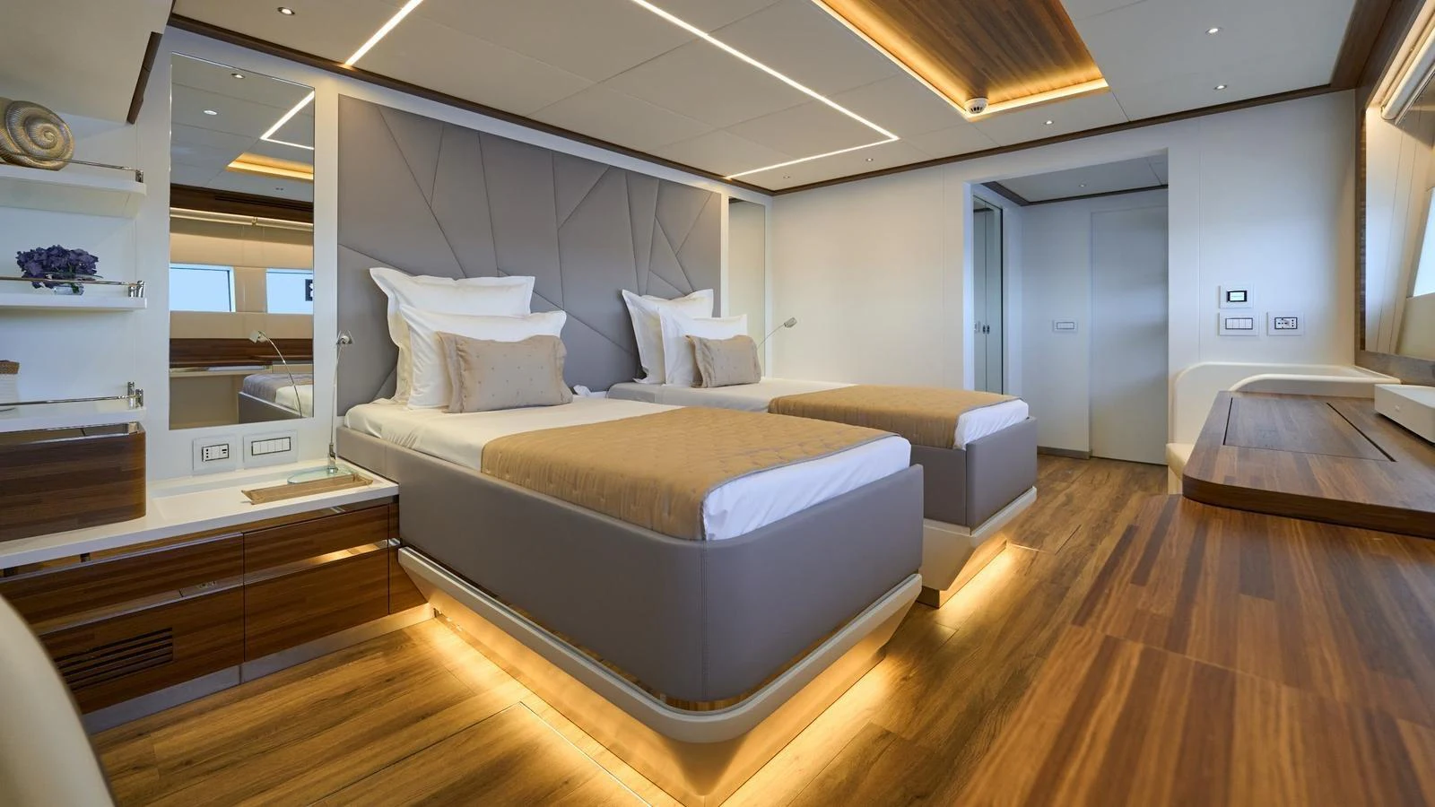 The guest stateroom features twin beds with modern decor and ambient lighting. aboard ATRAVERSIA Yacht for Sale