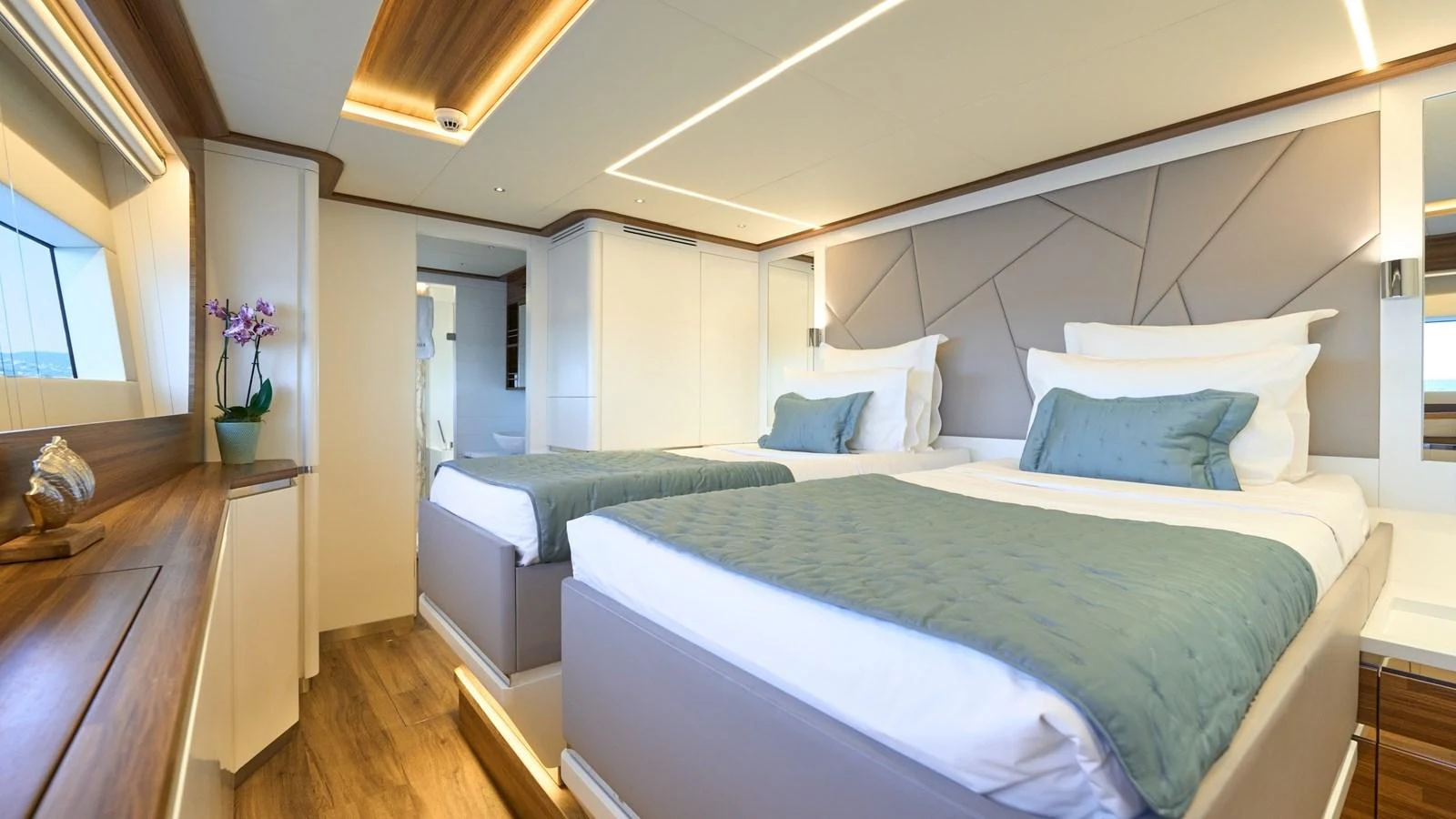 The guest stateroom features twin beds with luxurious bedding and modern decor. aboard ATRAVERSIA Yacht for Sale