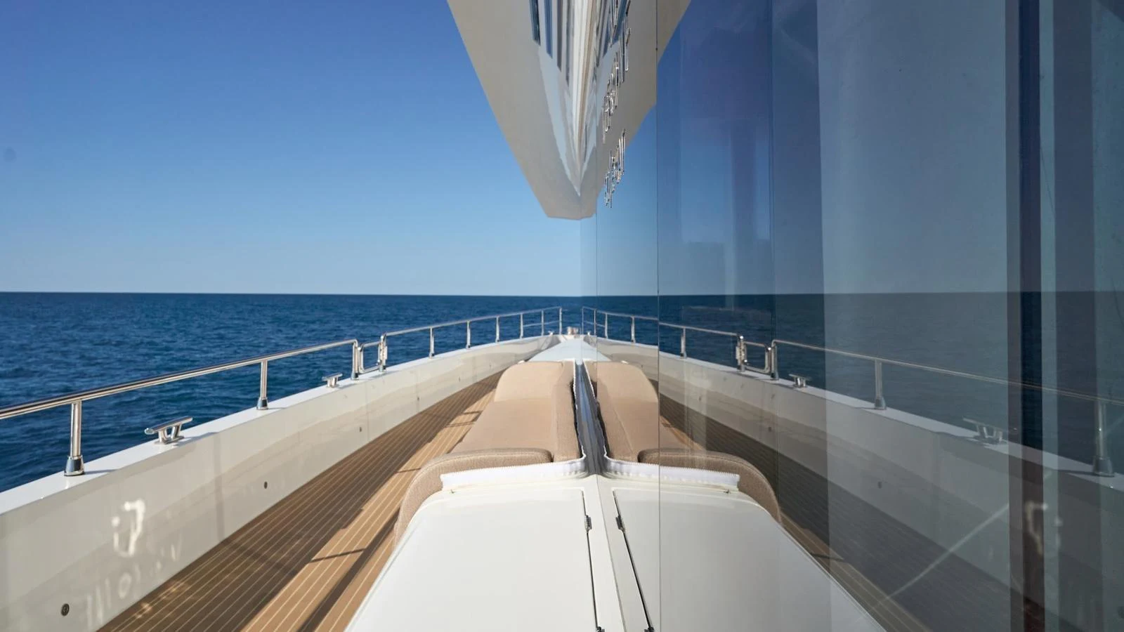 The sleek bow of the yacht reflects beautifully on the glass, showcasing its modern design against a serene ocean backdrop. aboard ATRAVERSIA Yacht for Sale