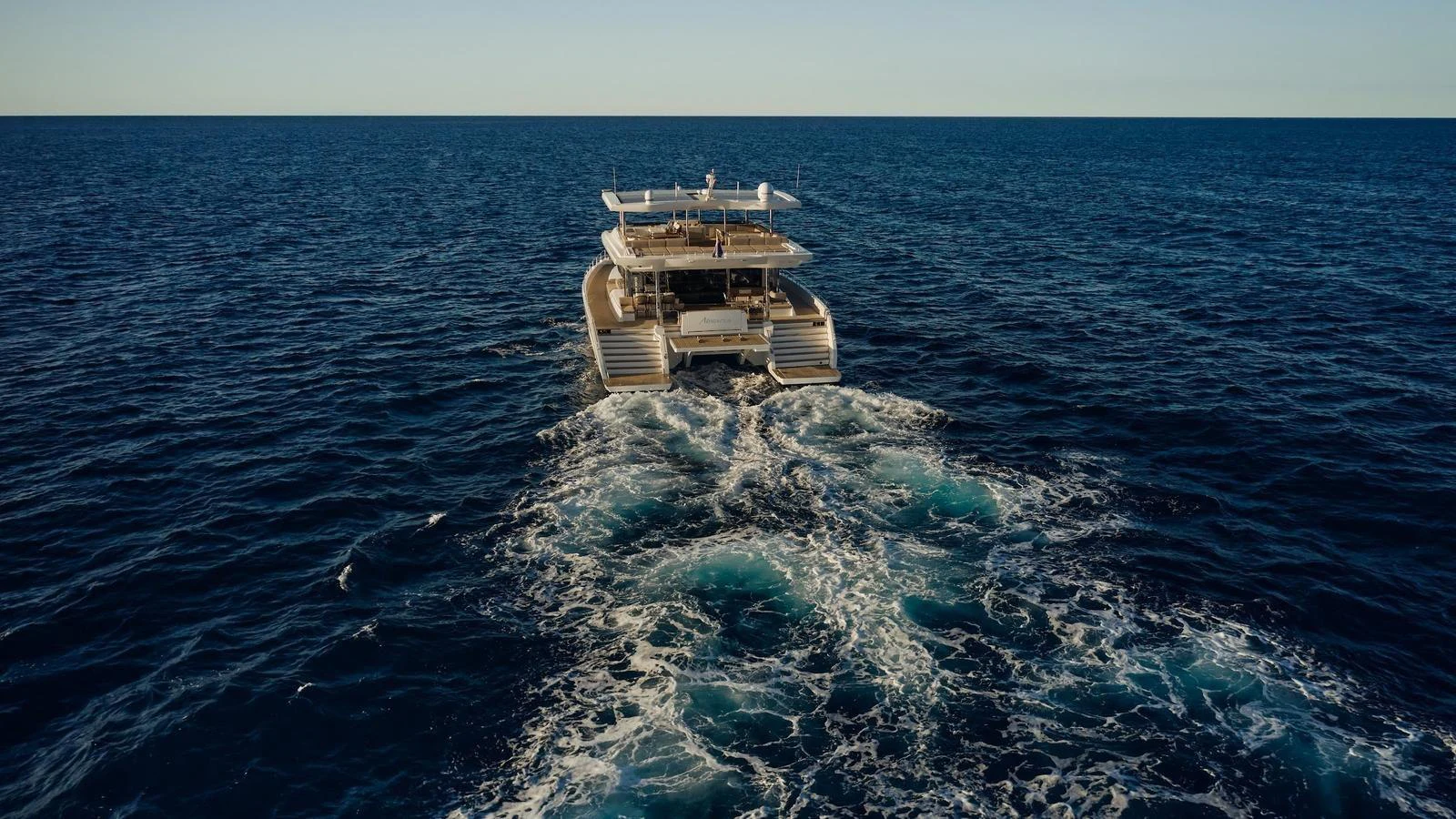 A luxurious yacht cruises through the open sea, leaving a trail of white foam in its wake. aboard ATRAVERSIA Yacht for Sale