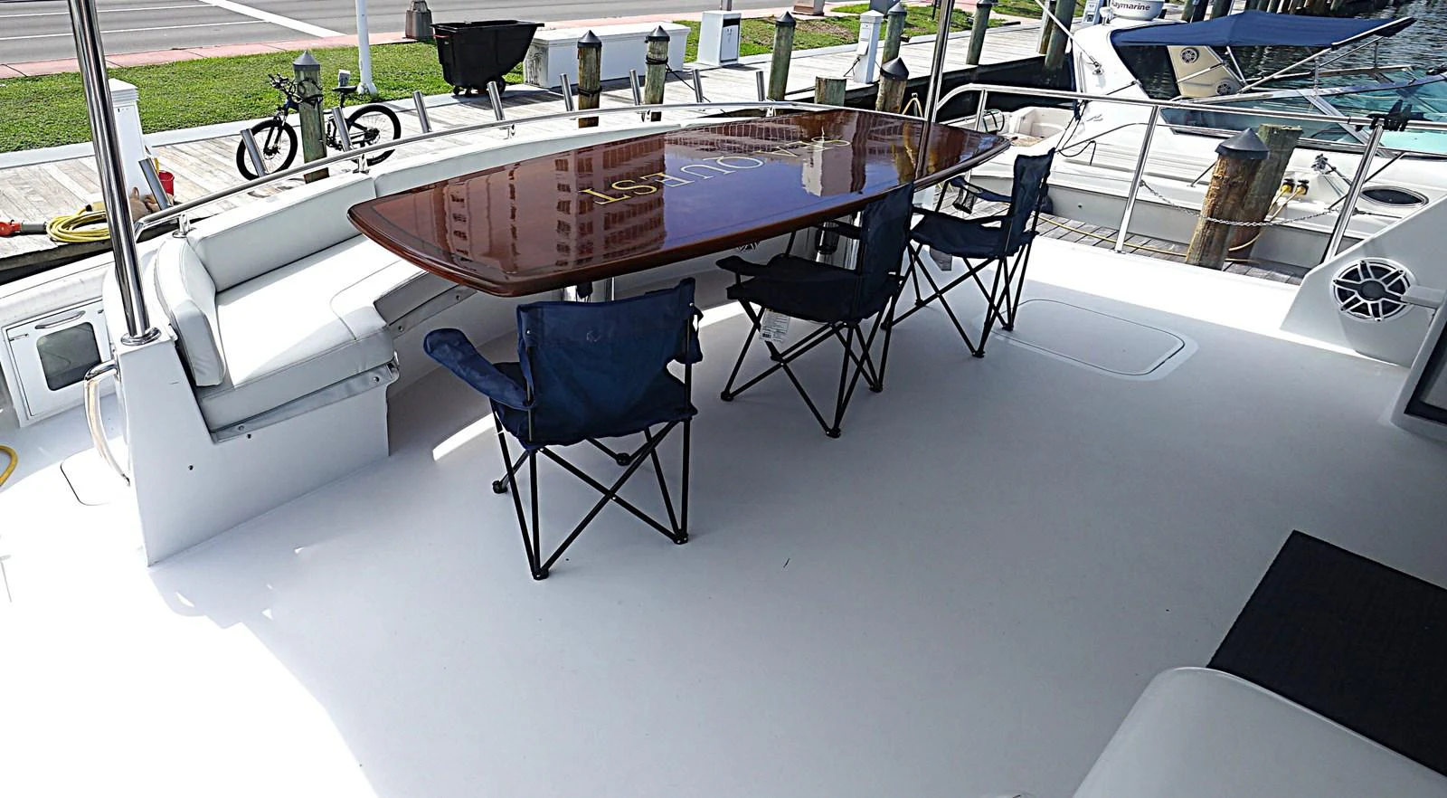 The aft deck features a spacious dining area with a polished wooden table and comfortable seating. aboard HATTERAS 92' Yacht for Sale