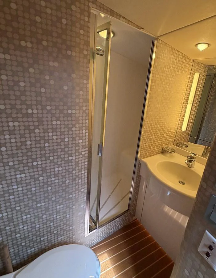The yacht's bathroom features a compact shower and a sleek sink area with modern lighting. aboard HATTERAS 92' Yacht for Sale