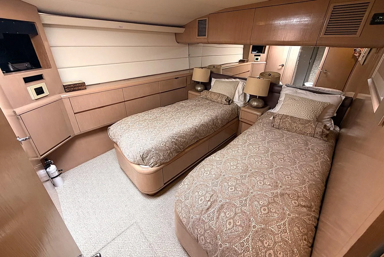 The guest stateroom features twin beds with elegant bedding and warm wood finishes. aboard HATTERAS 92' Yacht for Sale