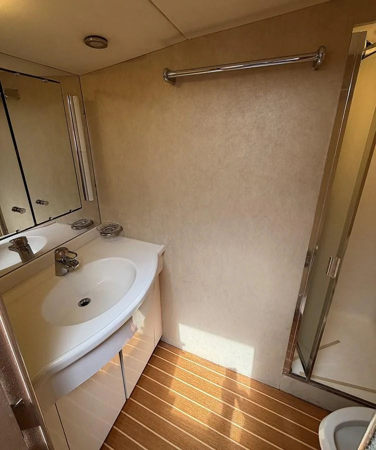 A well-appointed yacht bathroom with a modern sink and shower. aboard HATTERAS 92' Yacht for Sale