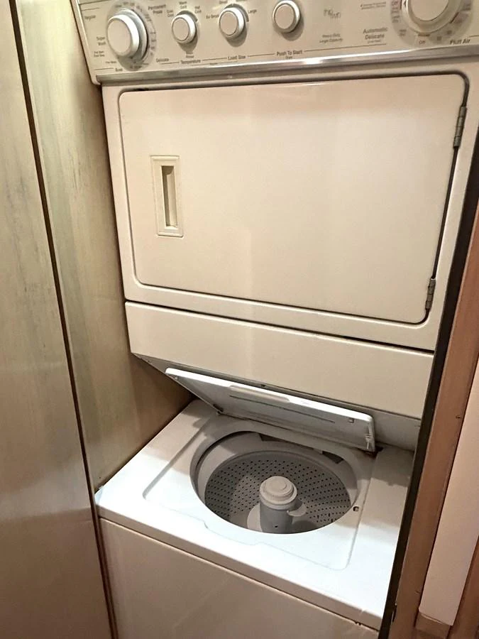 The yacht features a convenient laundry area with a stacked washer and dryer. aboard HATTERAS 92' Yacht for Sale
