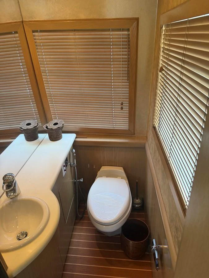 The yacht's head features a compact and well-appointed design with wooden accents and modern fixtures. aboard HATTERAS 92' Yacht for Sale