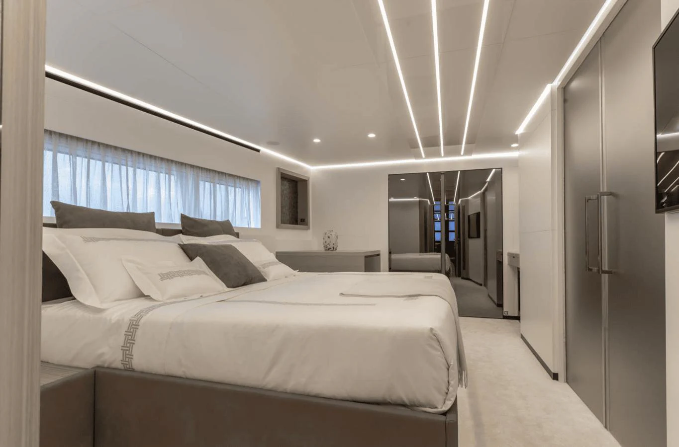 The master stateroom features a spacious bed with modern, sleek design elements and ambient lighting. aboard MANDAYACHT S07 SPIDER Yacht for Sale