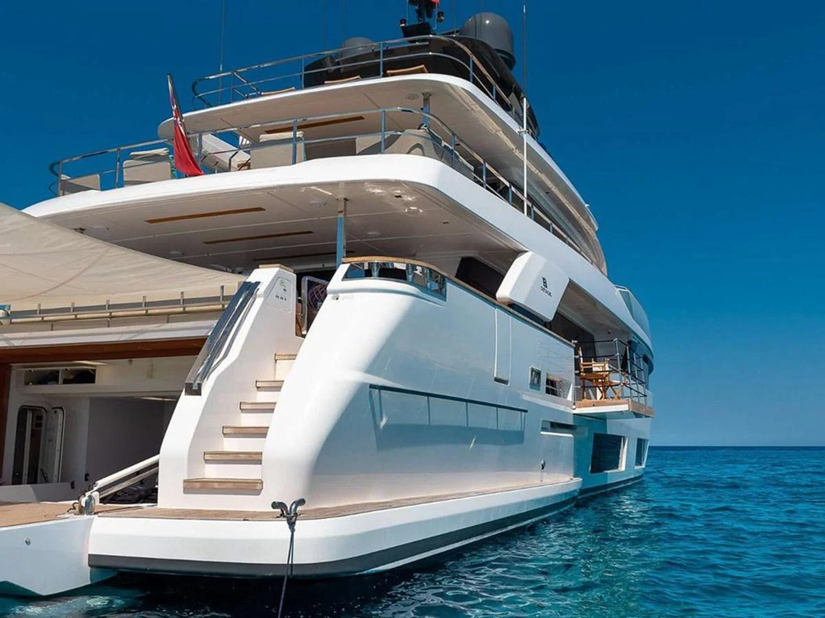 A luxurious yacht with multiple decks is anchored in clear blue waters. aboard ON Yacht for Sale