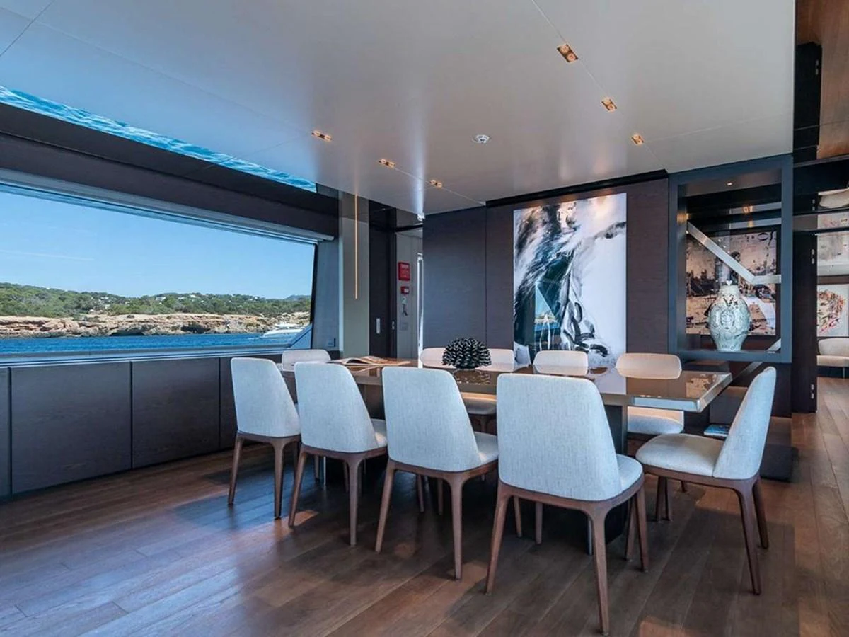 The yacht's dining area features a large table with elegant seating and expansive windows offering stunning views. aboard ON Yacht for Sale