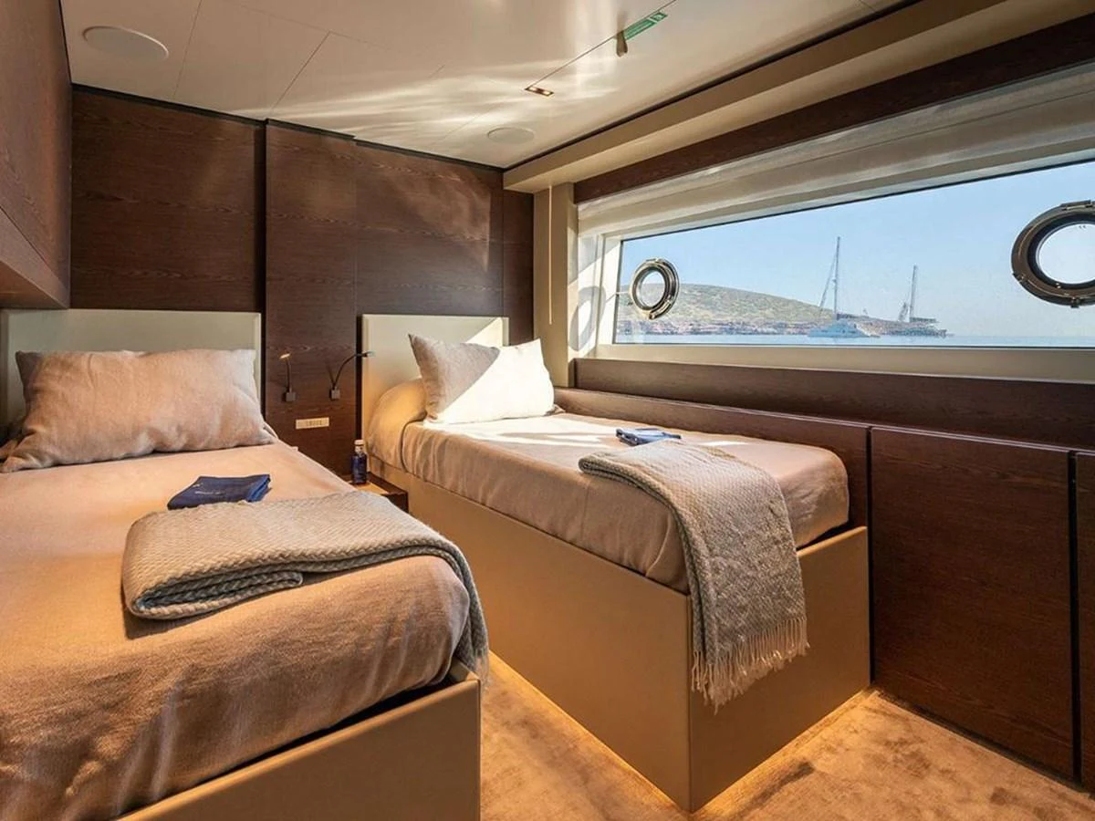 The guest stateroom features twin beds with a large window offering a scenic view. aboard ON Yacht for Sale
