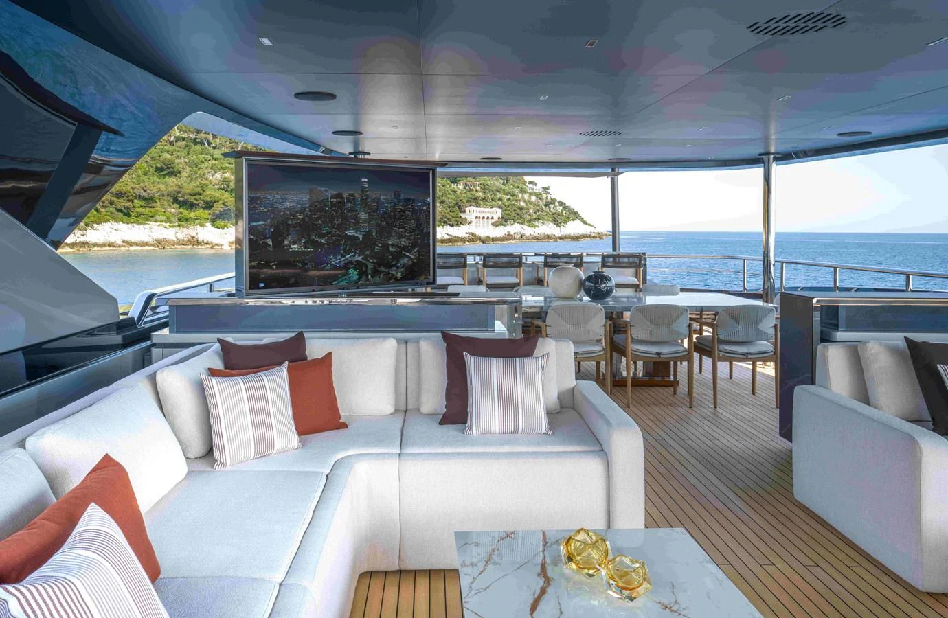 The aft deck offers a luxurious seating area with a large TV and stunning ocean views. aboard SAIRU Yacht for Sale