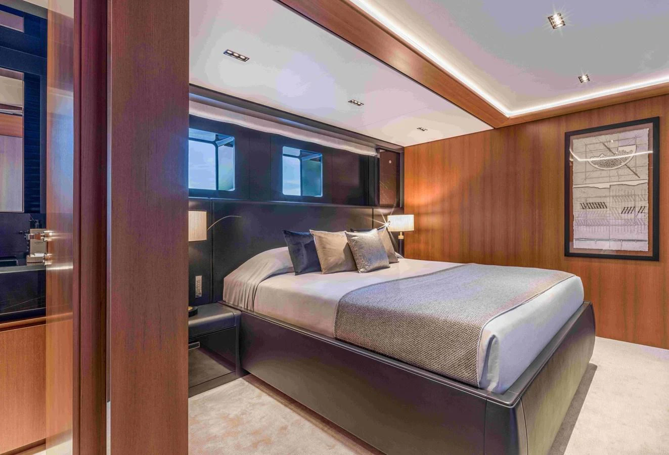 The stateroom features a luxurious bed with modern decor and warm lighting. aboard SAIRU Yacht for Sale