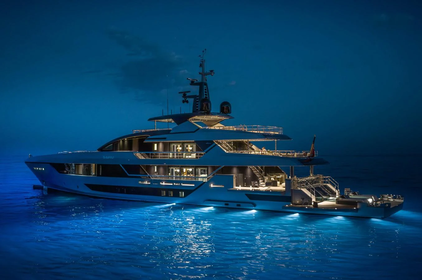 A luxurious yacht is beautifully illuminated at night, showcasing its elegant design and multiple decks. aboard SAIRU Yacht for Sale