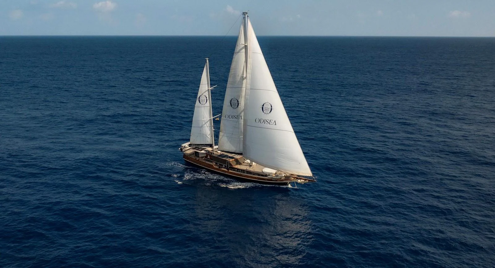 A stunning sailing yacht glides gracefully across the open sea under full sail. aboard ODISEA Yacht for Sale