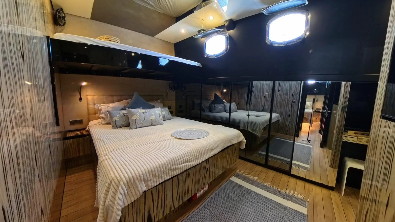 A cozy stateroom with a double bed, mirrored closet, and ambient lighting. aboard ODISEA Yacht for Sale
