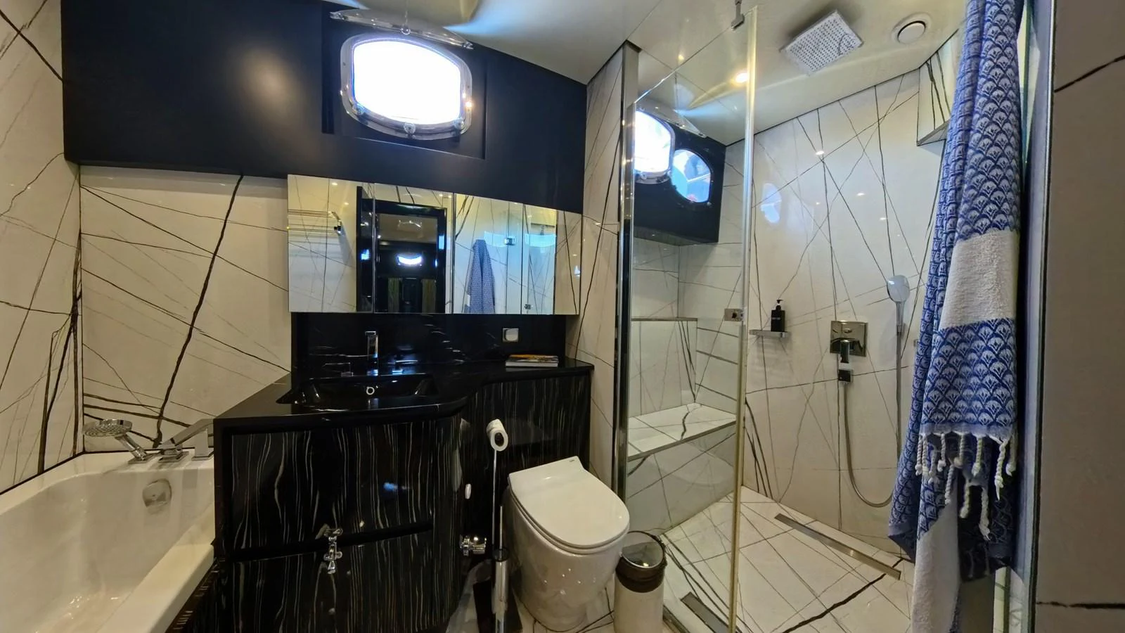 A modern yacht bathroom featuring a sleek design with a shower, toilet, and sink. aboard ODISEA Yacht for Sale