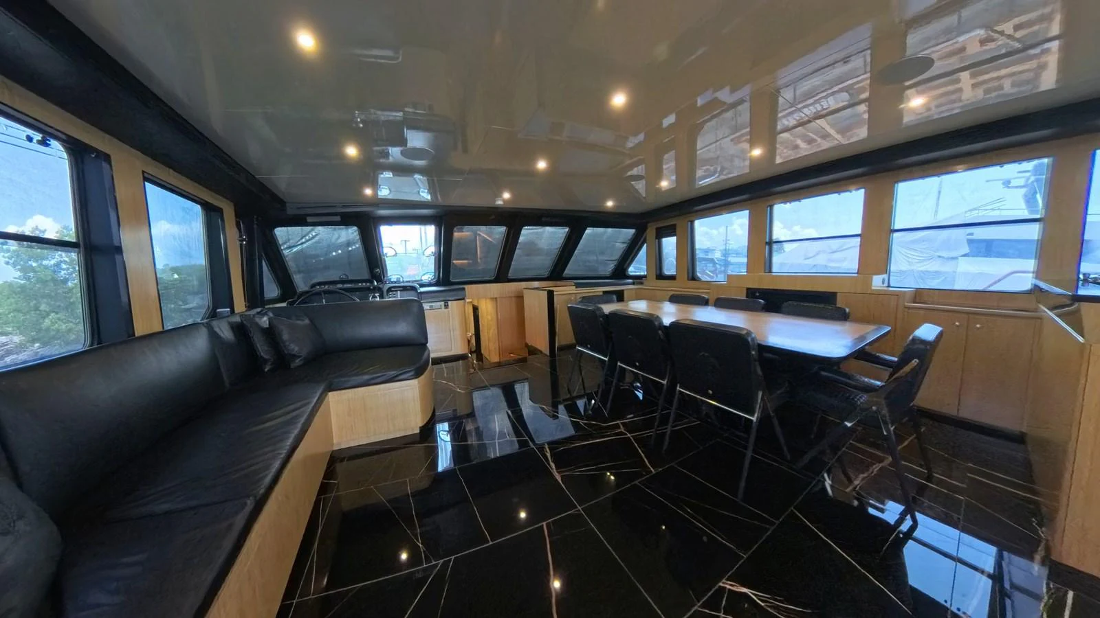 The yacht's salon features a spacious seating area with a large dining table, surrounded by panoramic windows. aboard ODISEA Yacht for Sale