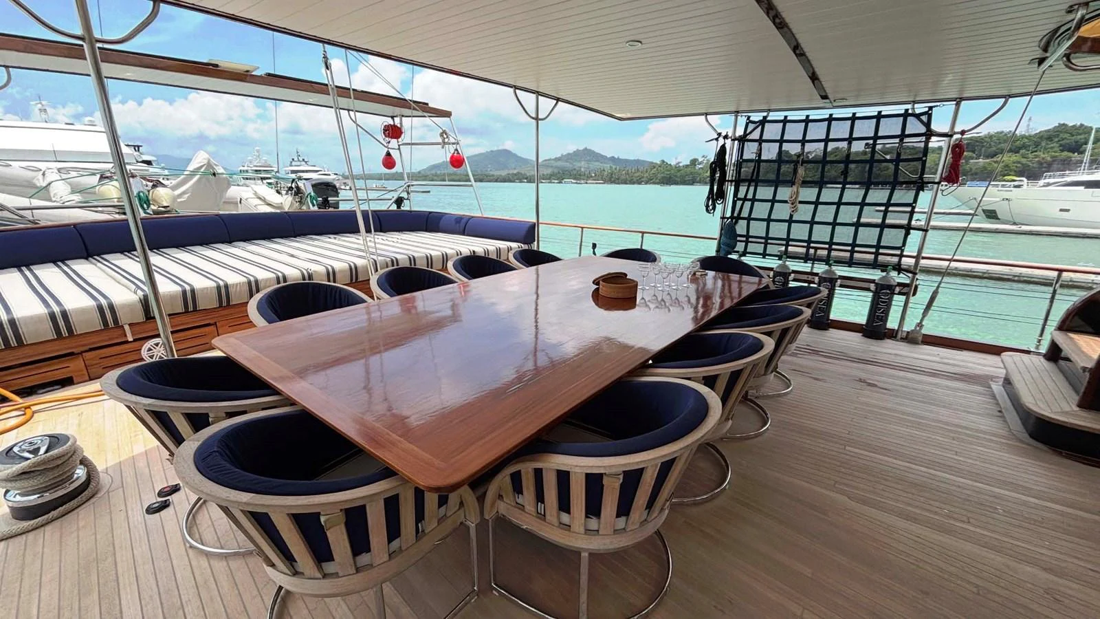The aft deck features a spacious dining area with a polished wooden table and comfortable seating, perfect for alfresco meals. aboard ODISEA Yacht for Sale