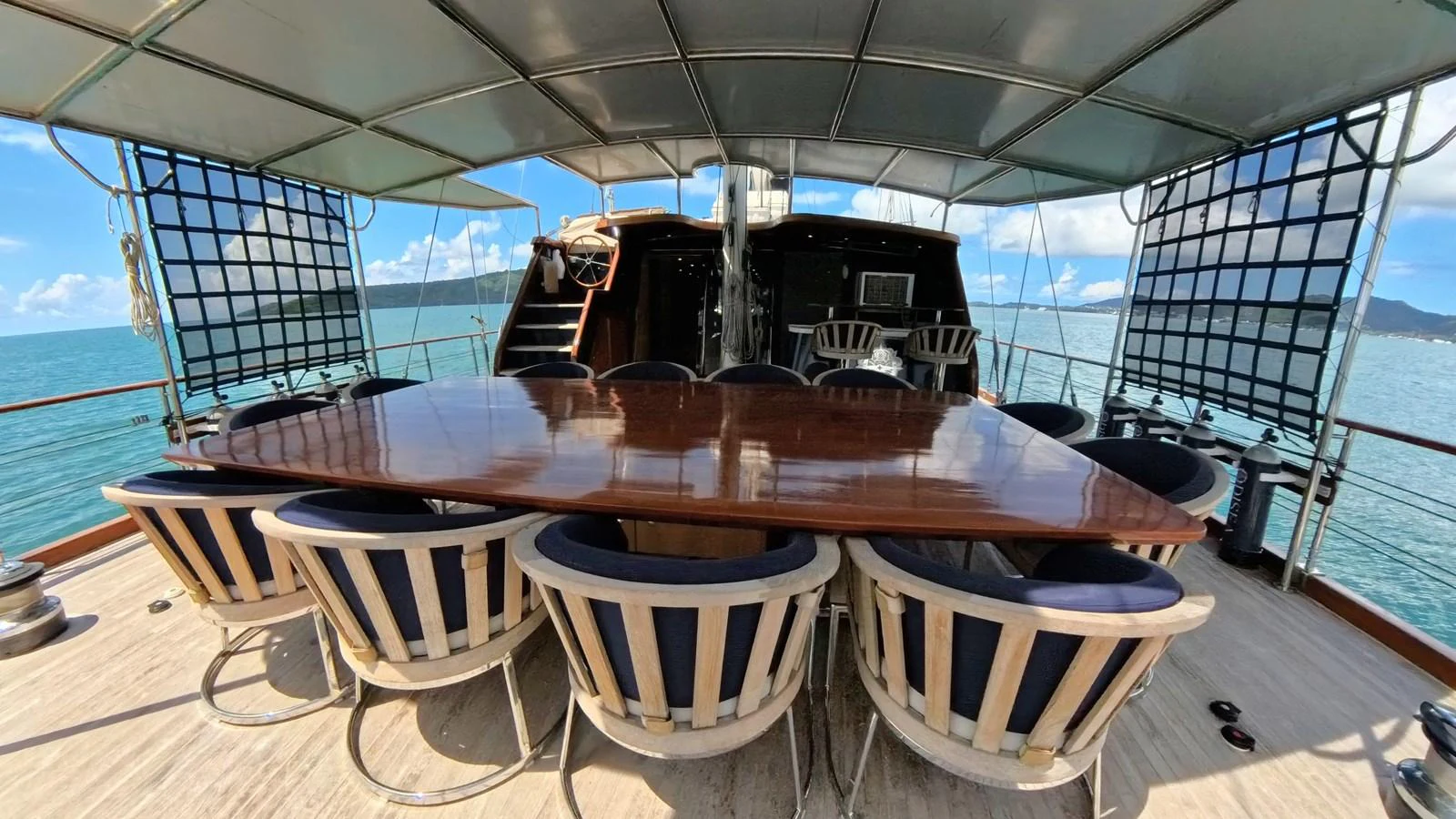 The aft deck features a spacious dining area with a large table and comfortable seating, perfect for alfresco meals with a view. aboard ODISEA Yacht for Sale