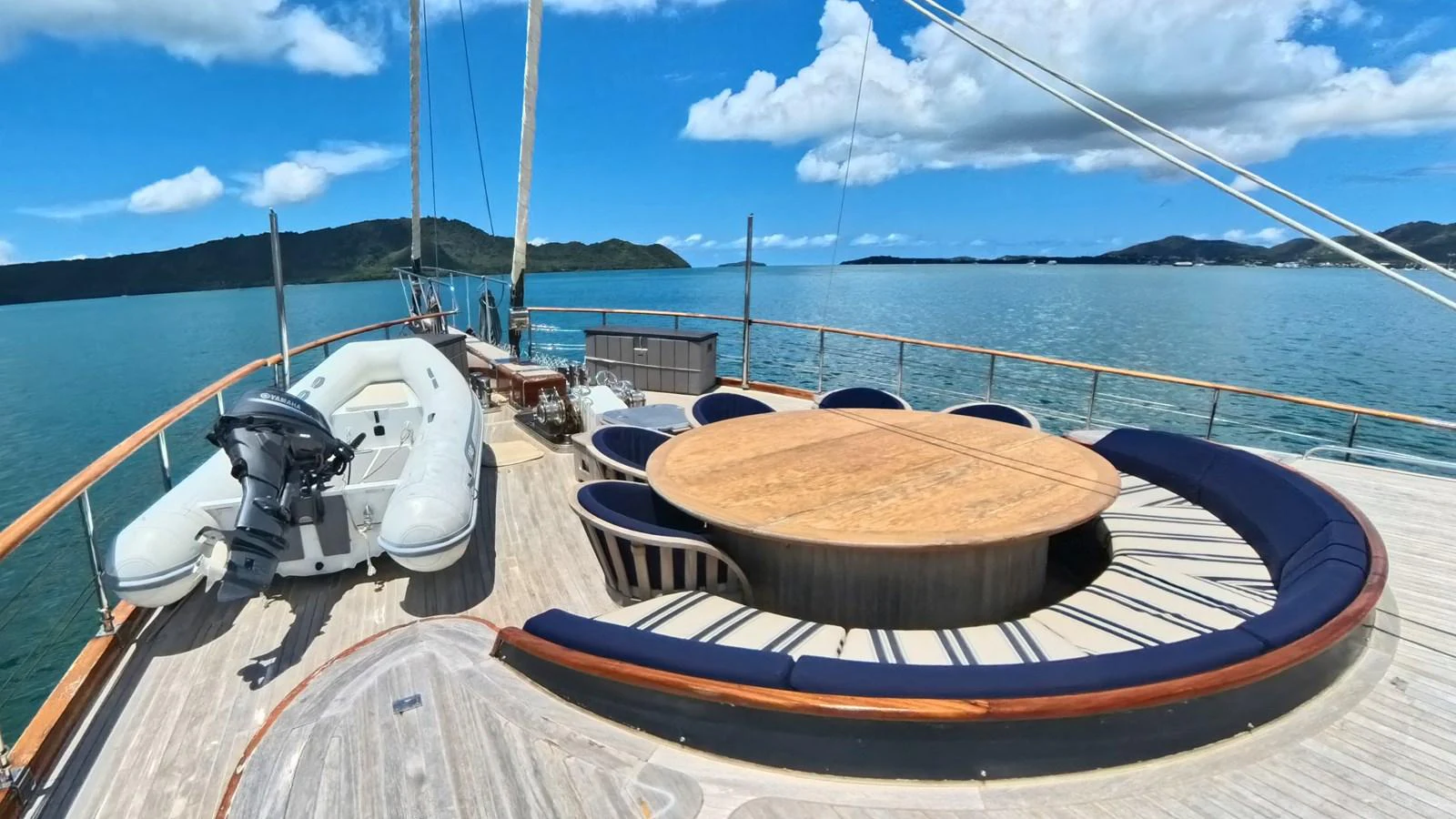 The aft deck features a spacious seating area with a round table, perfect for outdoor dining and relaxation. aboard ODISEA Yacht for Sale