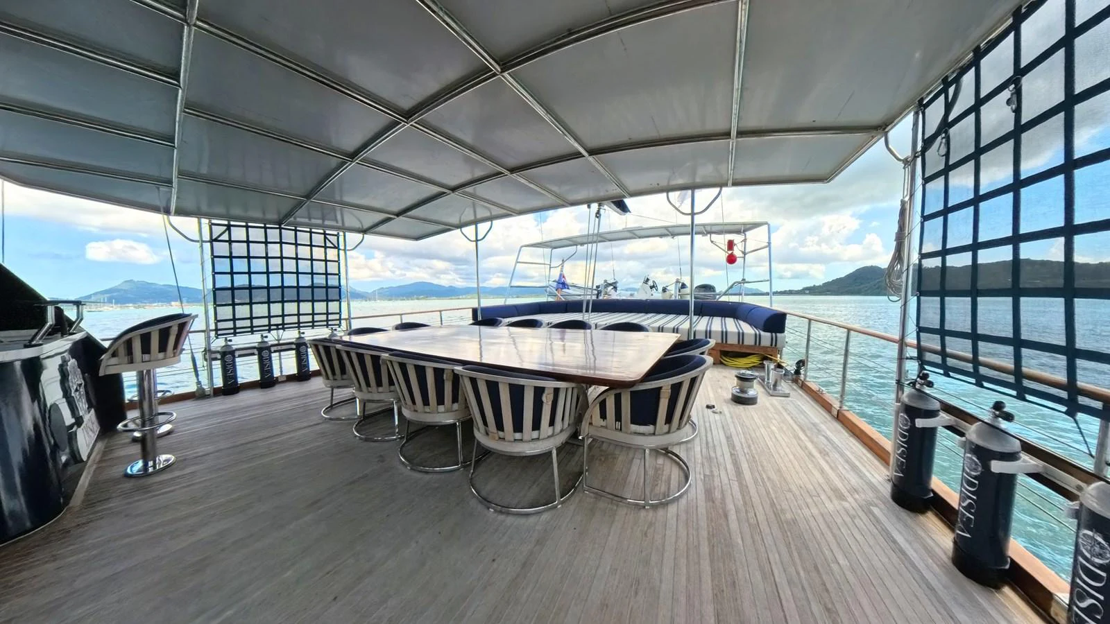 The aft deck features a spacious dining area with a large table and comfortable seating, perfect for alfresco meals with stunning sea views. aboard ODISEA Yacht for Sale