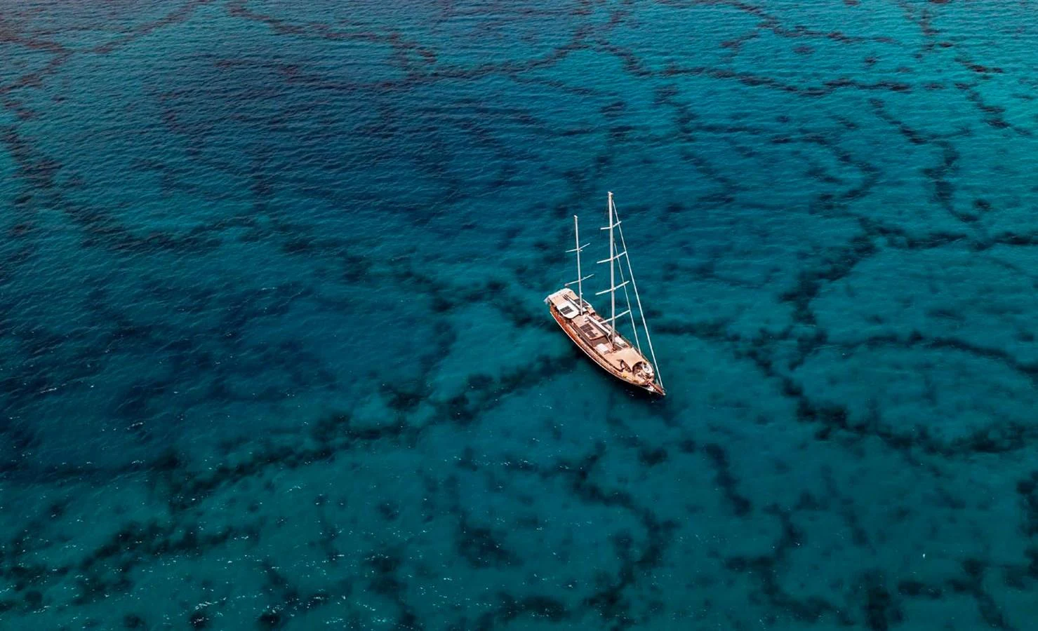 A stunning yacht sails gracefully on clear, turquoise waters, showcasing its elegant design. aboard ODISEA Yacht for Sale