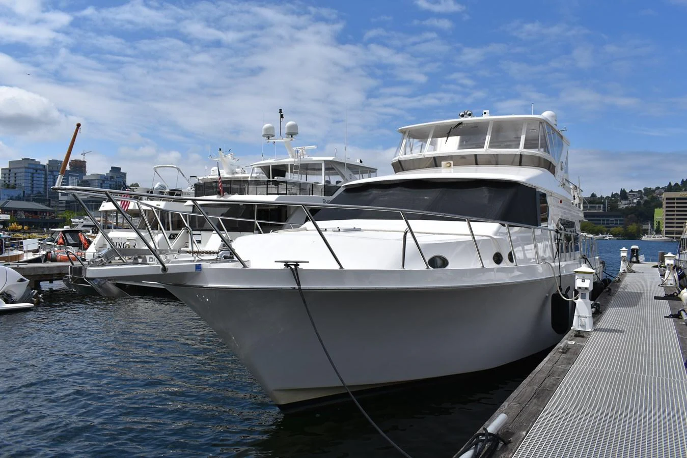 A sleek white yacht docked at a marina under a partly cloudy sky. aboard 64 OCEAN ALEXANDER Yacht for Sale