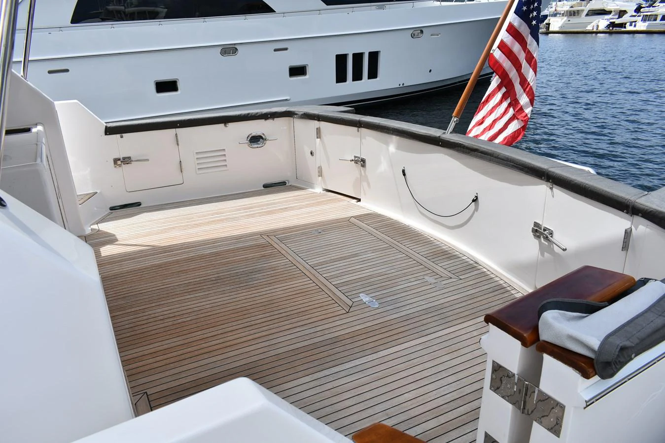 The aft deck features a spacious teak flooring area with an American flag displayed at the stern. aboard 64 OCEAN ALEXANDER Yacht for Sale