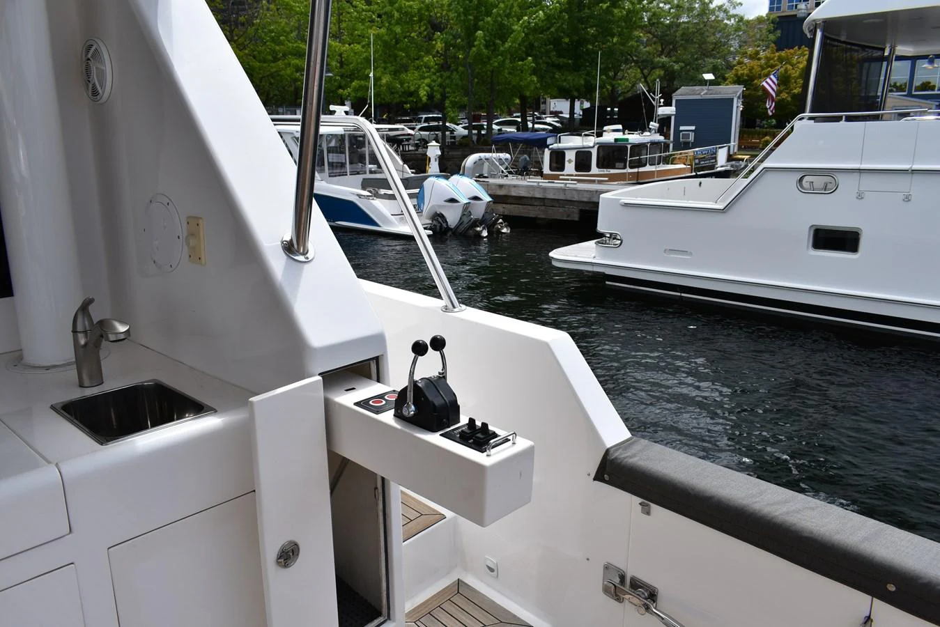 The image captures the helm station of a yacht, featuring control levers and a sink, with a marina in the background. aboard 64 OCEAN ALEXANDER Yacht for Sale