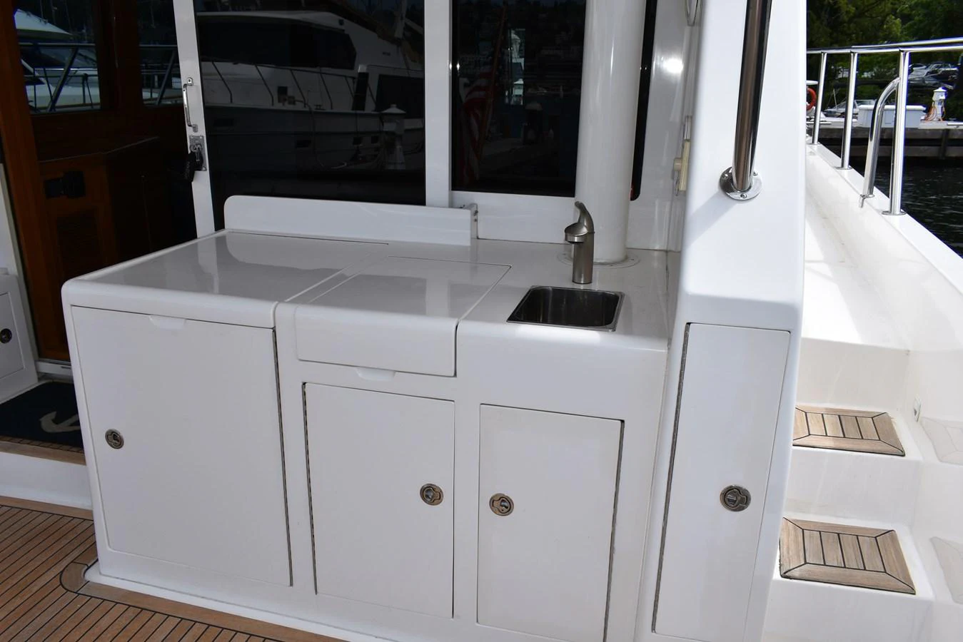 The yacht features a compact outdoor galley with a sink and storage cabinets. aboard 64 OCEAN ALEXANDER Yacht for Sale