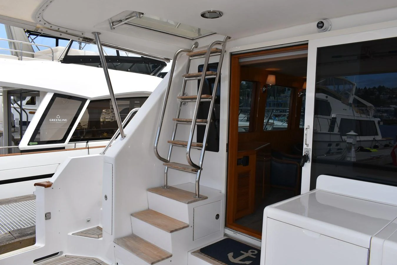 The aft deck features a stainless steel ladder leading to the upper deck and a sliding glass door to the interior. aboard 64 OCEAN ALEXANDER Yacht for Sale