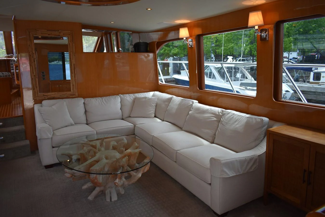 The salon features a spacious white sectional sofa and a unique glass coffee table with a coral-like base, offering a comfortable and stylish lounging area. aboard 64 OCEAN ALEXANDER Yacht for Sale