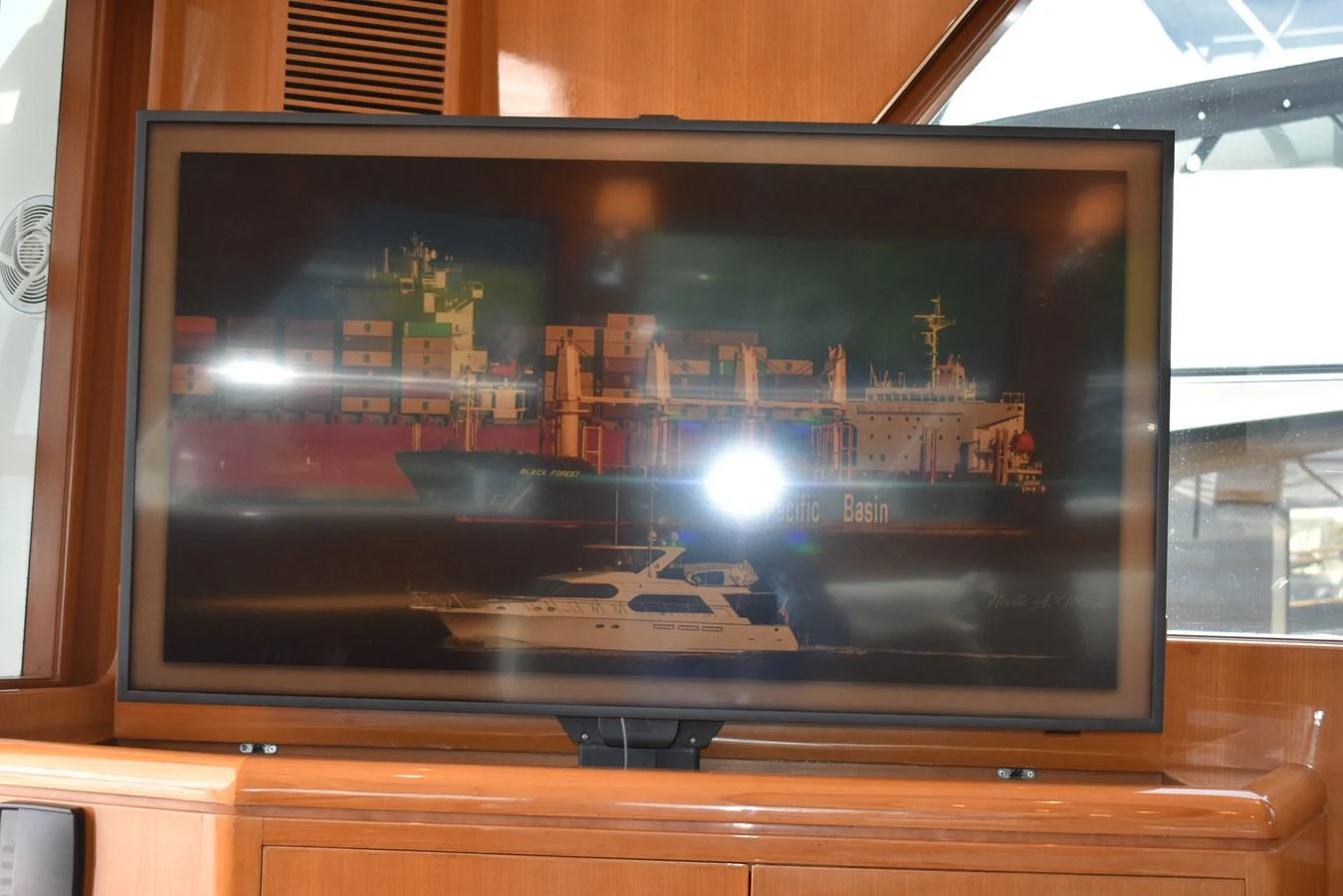 A television screen inside the yacht displays an image of a container ship and a yacht. aboard 64 OCEAN ALEXANDER Yacht for Sale