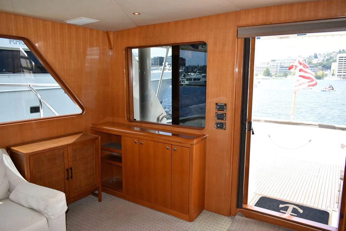 The interior features a cozy seating area with wooden cabinetry and a view of the exterior deck through large windows. aboard 64 OCEAN ALEXANDER Yacht for Sale