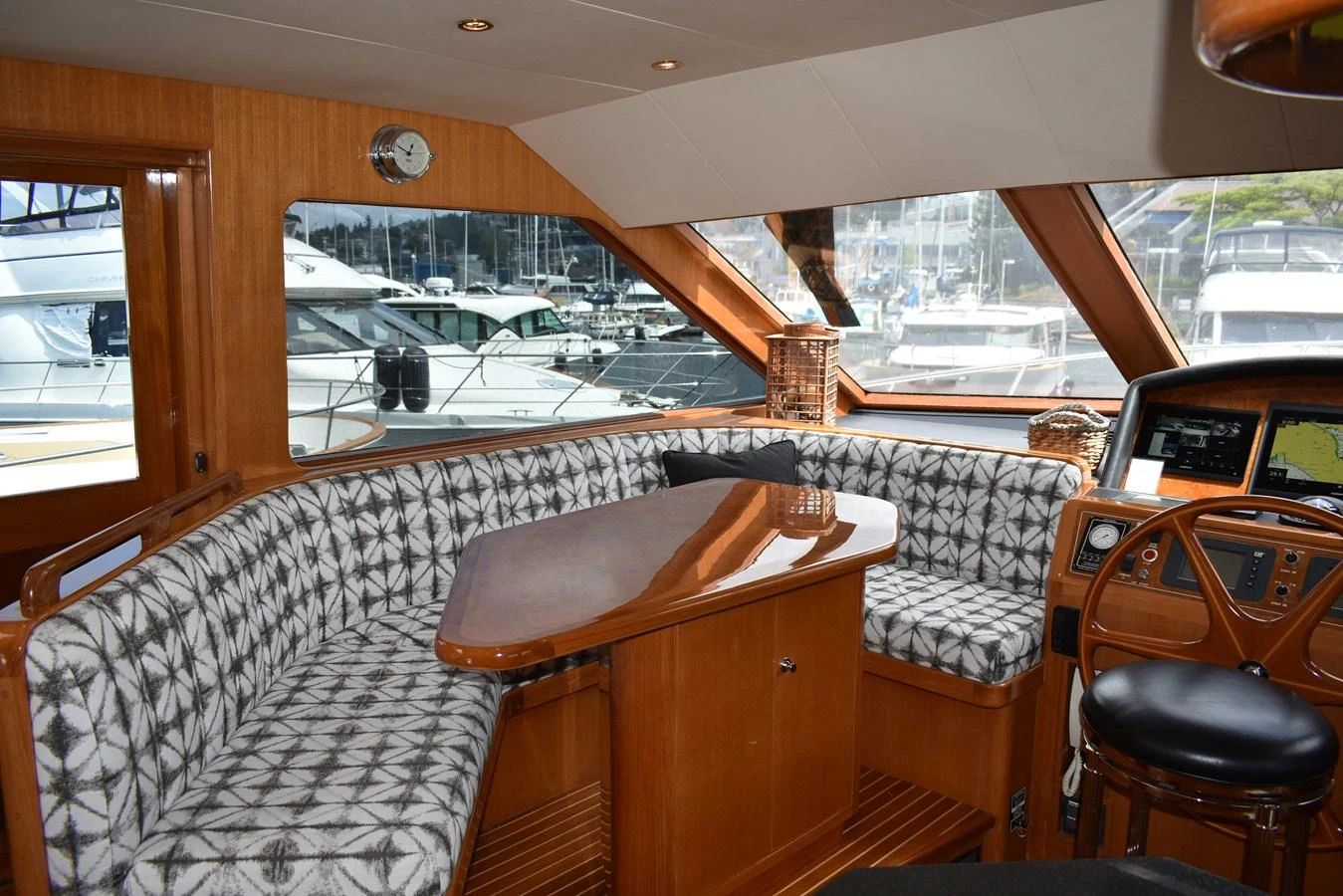 The saloon features a cozy seating area with a wooden table and large windows offering marina views. aboard 64 OCEAN ALEXANDER Yacht for Sale