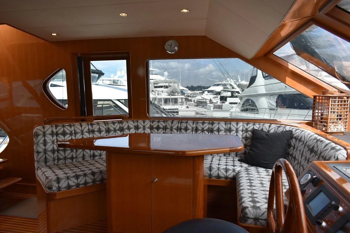 The salon features a cozy seating area with patterned cushions and a wooden table, offering a comfortable space to relax while enjoying the view of the marina. aboard 64 OCEAN ALEXANDER Yacht for Sale