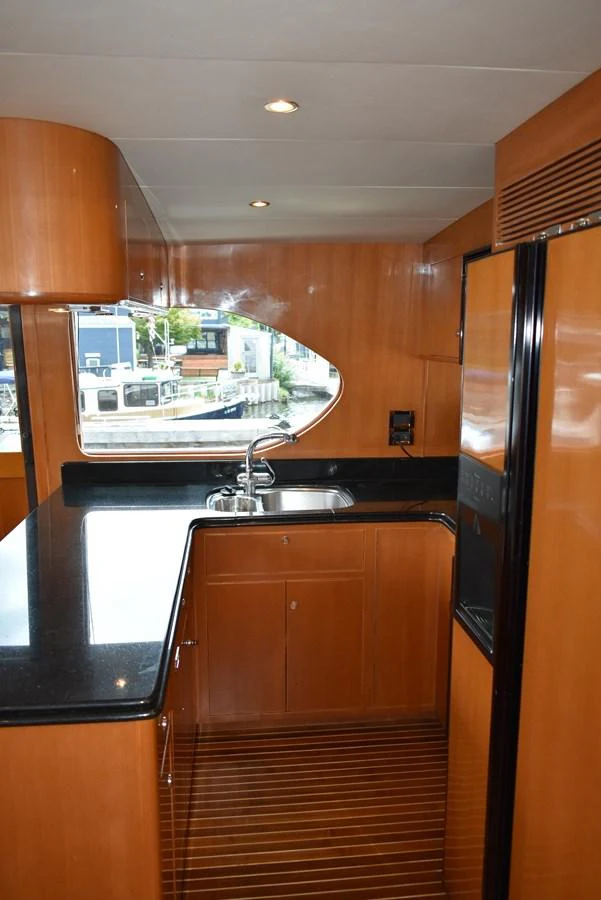 The yacht's galley features sleek wooden cabinetry and a polished black countertop, offering a modern and functional space. aboard 64 OCEAN ALEXANDER Yacht for Sale