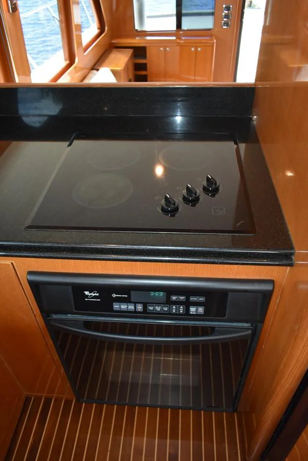 The galley features a sleek black cooktop and modern oven, set against rich wooden cabinetry. aboard 64 OCEAN ALEXANDER Yacht for Sale