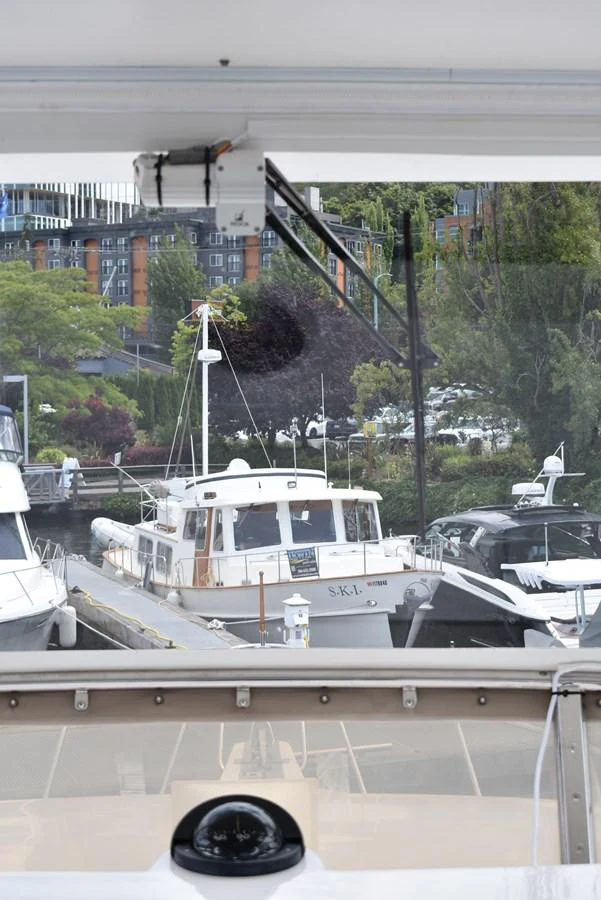 A view of multiple yachts docked at a marina, with a focus on a white yacht in the center. aboard 64 OCEAN ALEXANDER Yacht for Sale