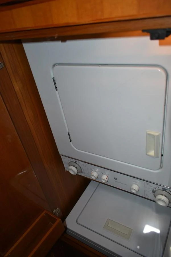 The yacht features a compact and efficient laundry area with a stacked washer and dryer. aboard 64 OCEAN ALEXANDER Yacht for Sale