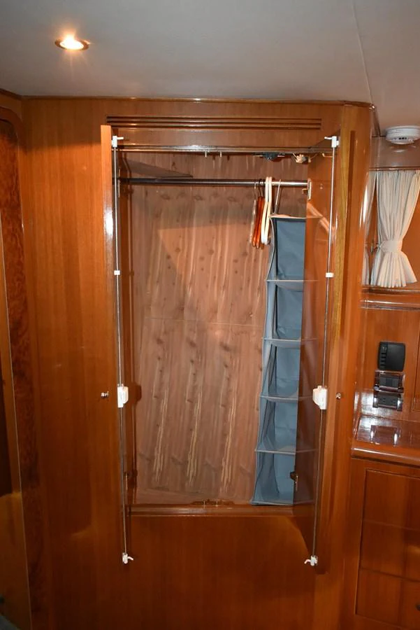 A well-organized closet with wooden paneling and ample storage space. aboard 64 OCEAN ALEXANDER Yacht for Sale
