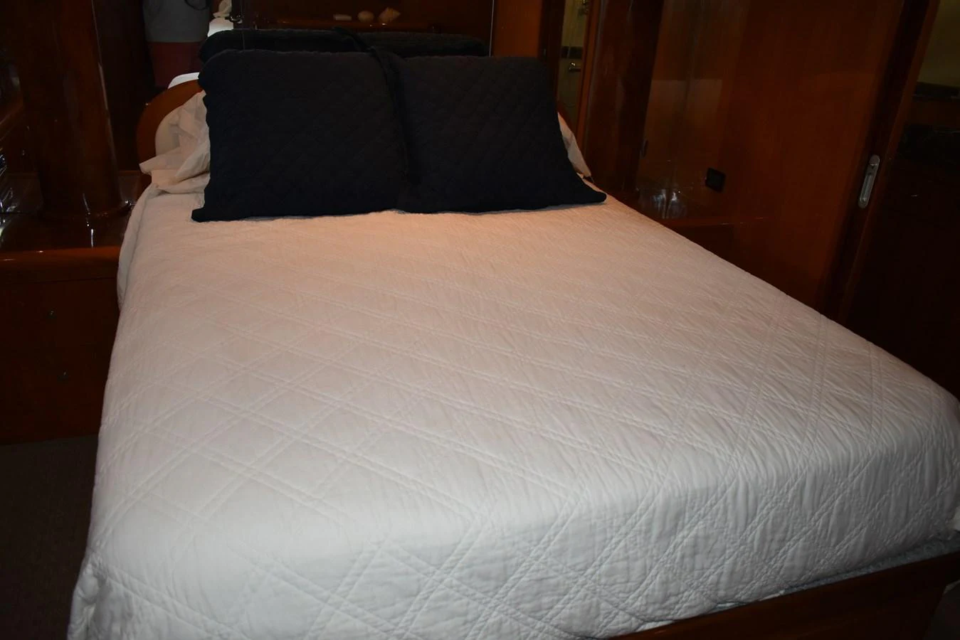A cozy stateroom featuring a neatly made bed with dark pillows. aboard 64 OCEAN ALEXANDER Yacht for Sale