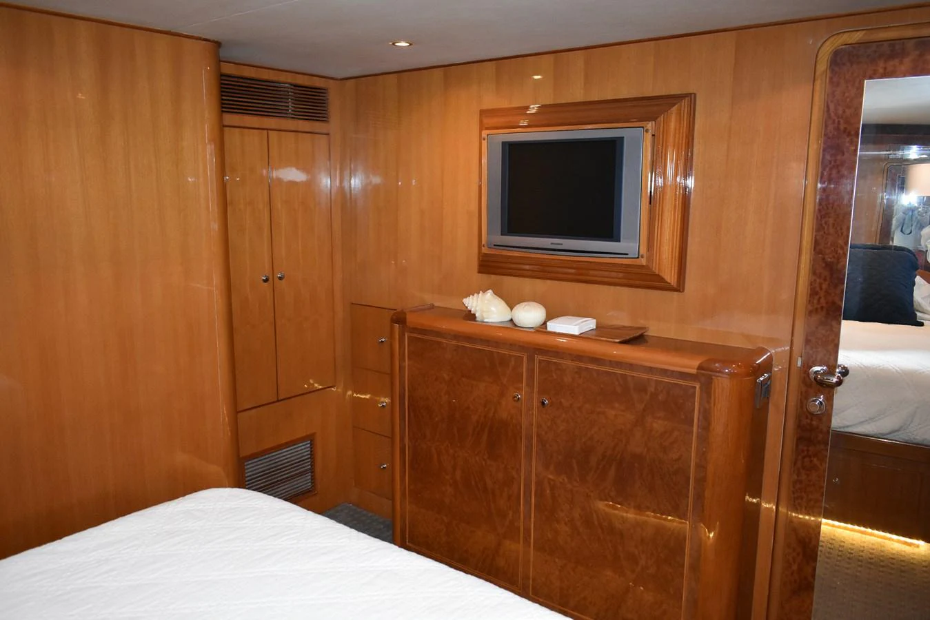 The stateroom features warm wood paneling and a mounted flat-screen TV for a cozy and inviting atmosphere. aboard 64 OCEAN ALEXANDER Yacht for Sale