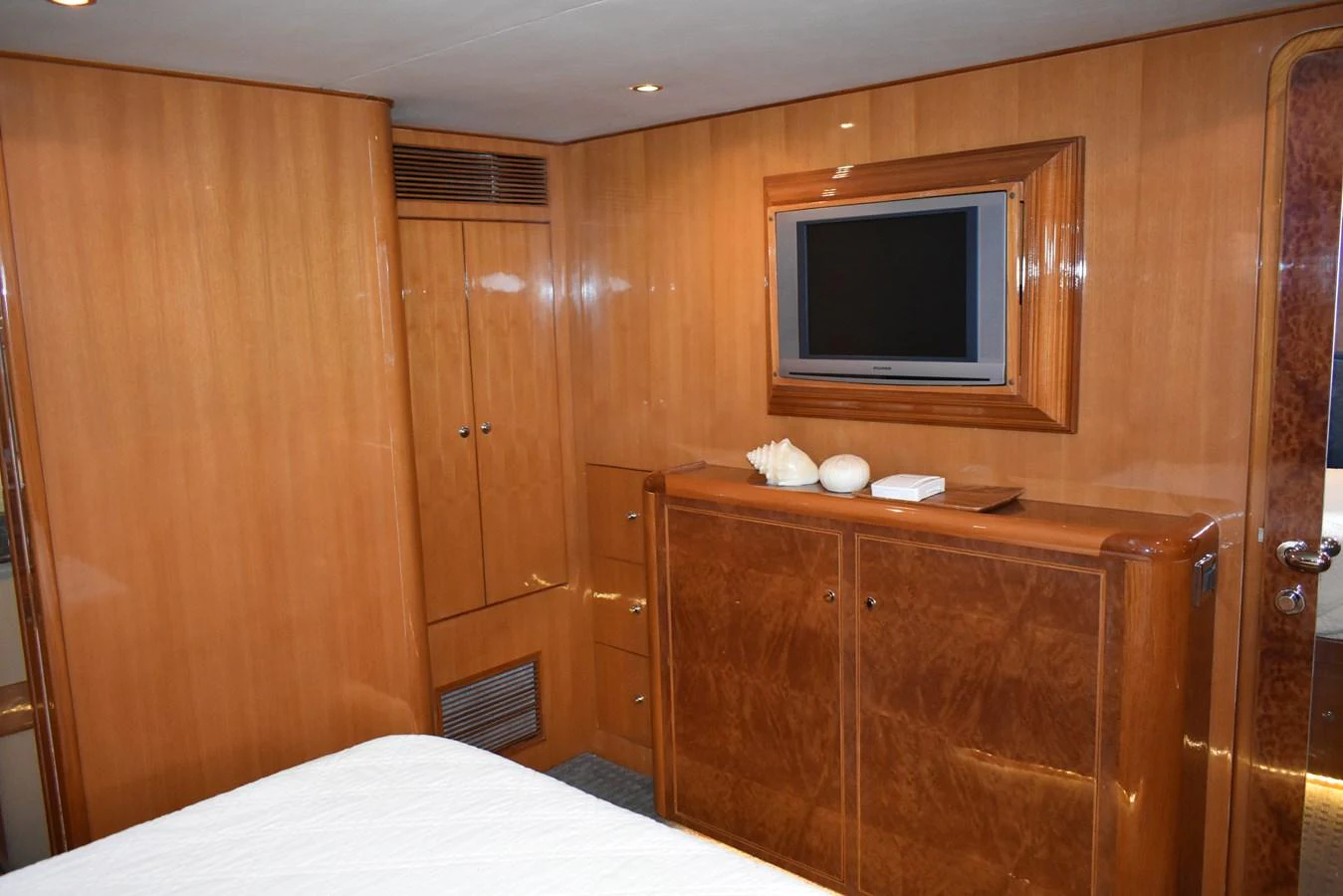 A cozy yacht cabin featuring wooden cabinetry and a mounted flat-screen TV. aboard 64 OCEAN ALEXANDER Yacht for Sale