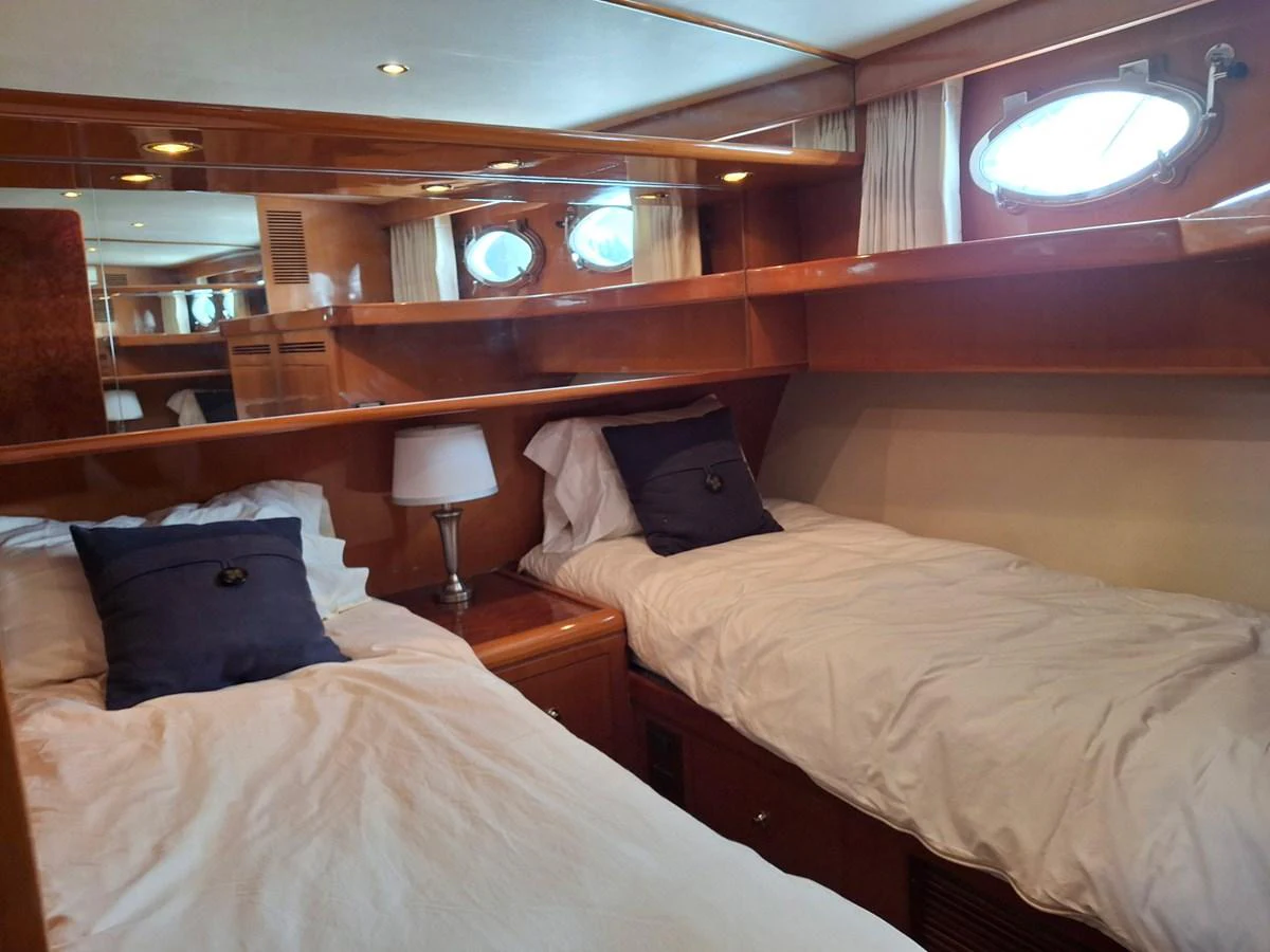 The twin stateroom features cozy twin beds with elegant wooden finishes and porthole windows. aboard 64 OCEAN ALEXANDER Yacht for Sale