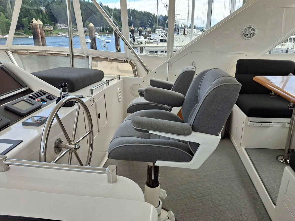 The helm area features comfortable seating and a modern steering wheel with a view of the marina. aboard 64 OCEAN ALEXANDER Yacht for Sale