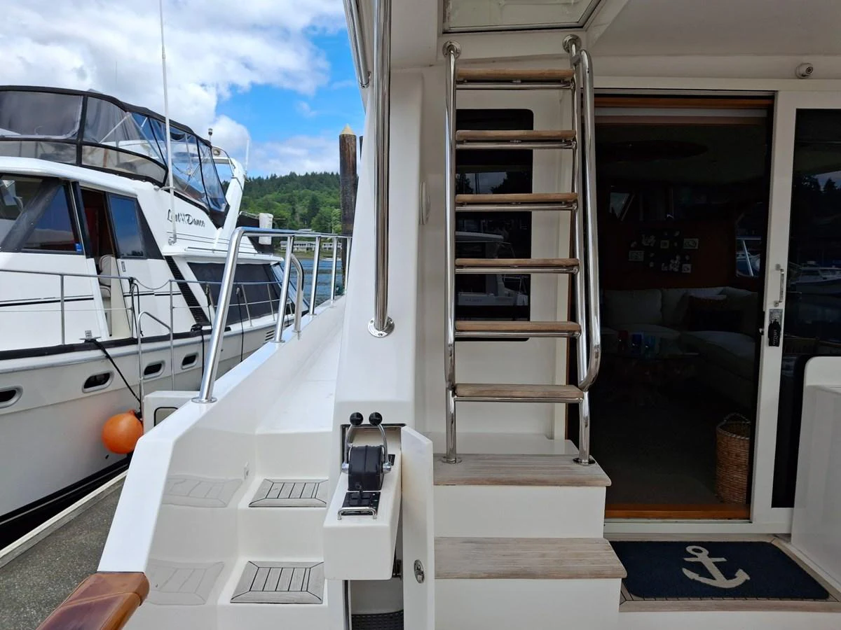 The aft deck features a ladder leading to the upper deck and a doorway to the interior. aboard 64 OCEAN ALEXANDER Yacht for Sale