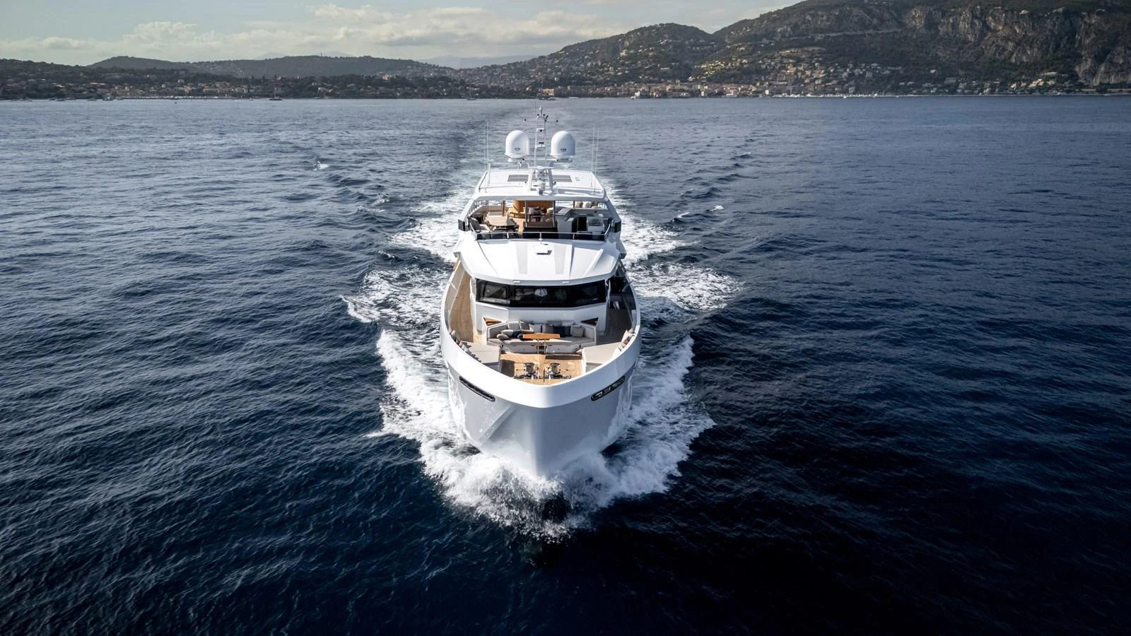 A luxurious yacht cruises through serene waters with a stunning backdrop of coastal hills. aboard NUMARINE 37XP#22 Yacht for Sale